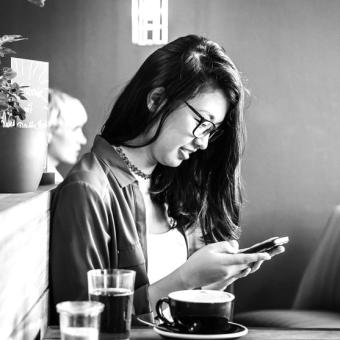 Young woman sitting in cafe using smartphone